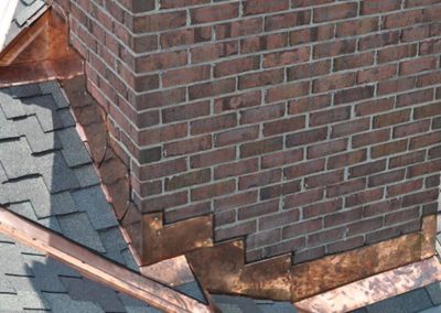Close up of chimney copper flashing with red brick chimney